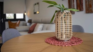 Ein runder Holztisch mit einem gewebten Pflanzgefäß und einer rosa Tischdecke.