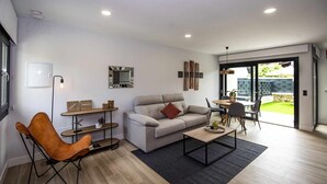 Ein modernes Wohnzimmer mit einer Couch, einem Couchtisch und einem Essbereich mit Stühlen.