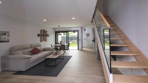 Ein modernes Wohnzimmer mit Sofa, Couchtisch und einer Treppe.