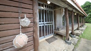 Een houten gebouw met veranda, een schuifdeur met glas en macramé decoraties.