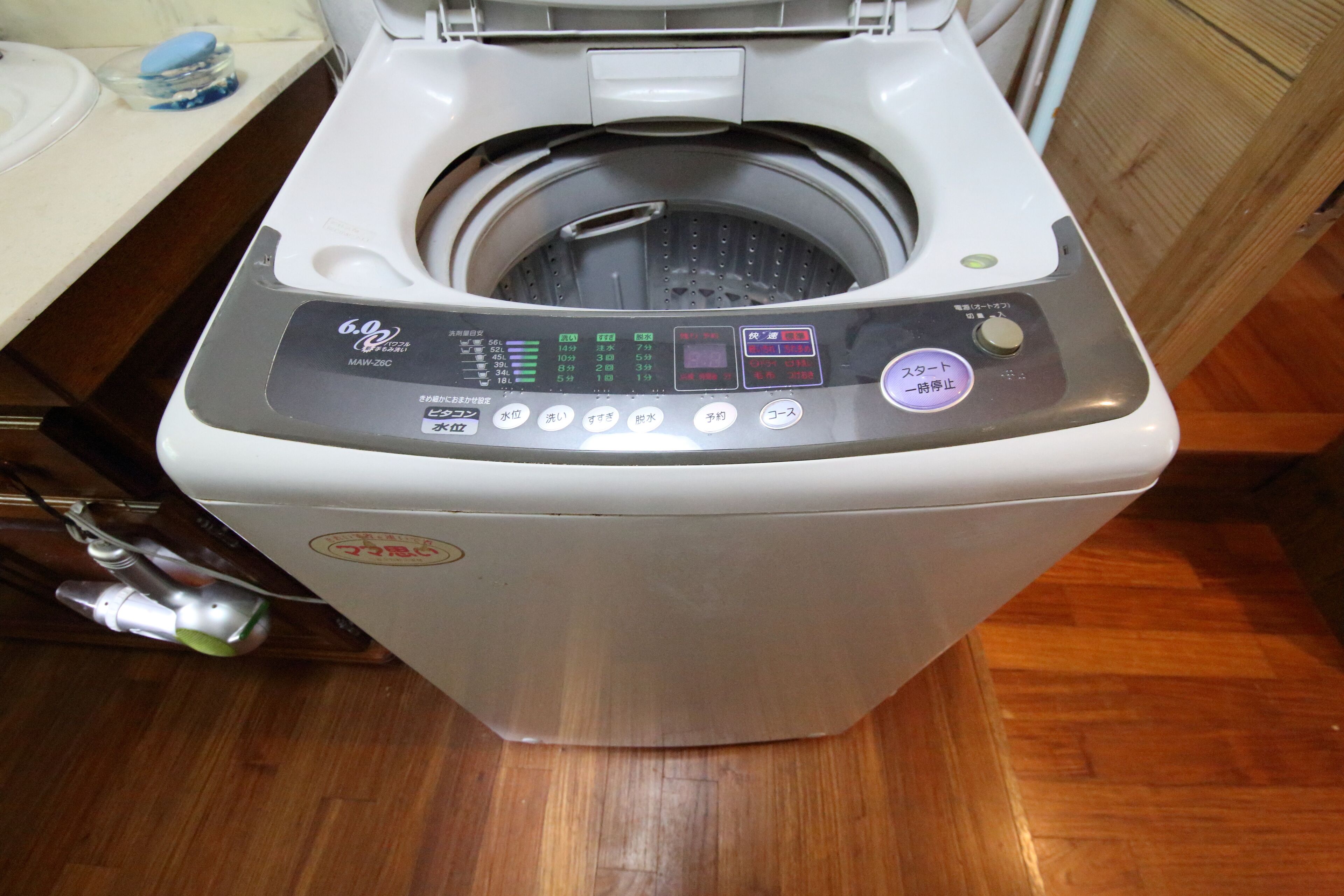 A front-loading washing machine with a control panel, a water inlet, and a drain hose.