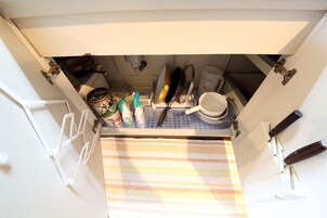 Una cocina con un felpudo a rayas, un lavabo blanco y diferentes utensilios de cocina.
