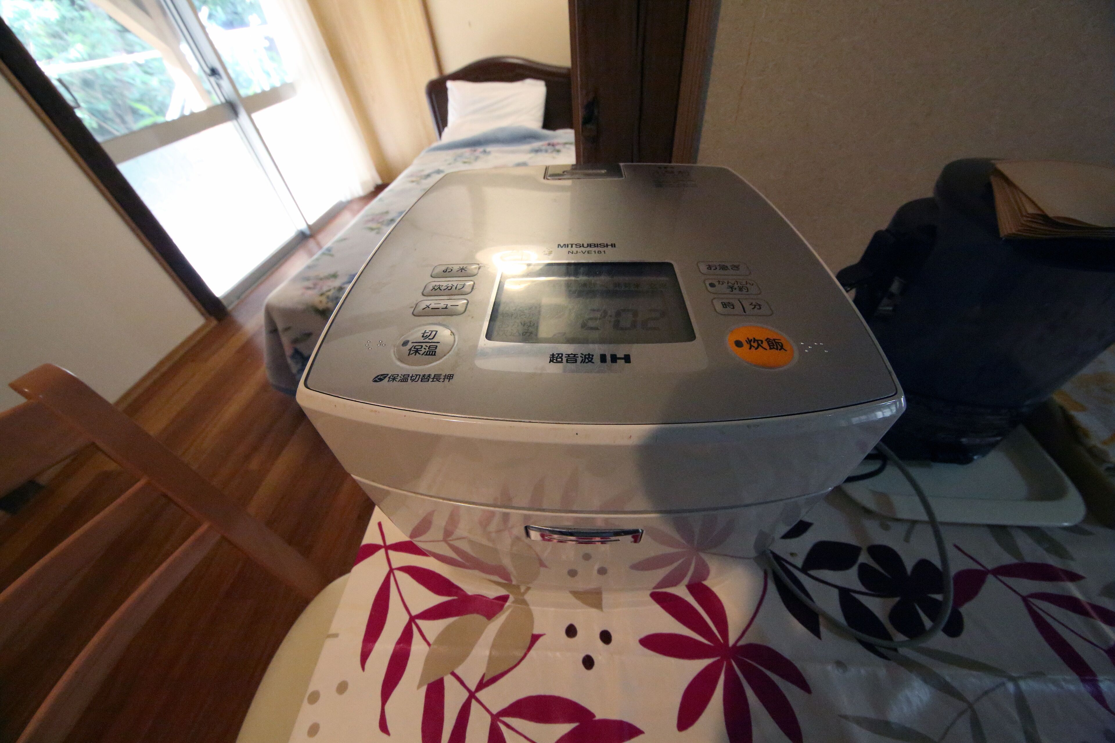 A Mitsubishi air fryer on a bed with a floral bedspread.