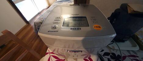 A Mitsubishi air fryer on a bed with a floral bedspread.