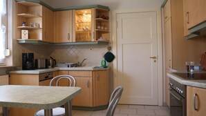Eine kleine Küche mit Holzausstattung, einem eingebauten Ofen und einer Essecke mit zwei Stühlen.