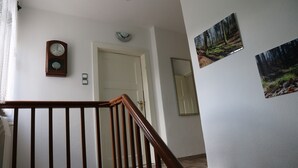 Eine Treppe mit hölzernen Geländern, einer Wanduhr und zwei gerahmten Bildern.