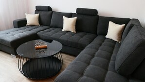 Ein modulares Sofa mit rundem Couchtisch und einem kleinen Beistelltisch, alles in einer neutralen Farbgebung.