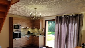 A modern kitchen with wooden cabinets, a built-in oven, and a large window with curtains. - House with sauna. Internet, Comfortable, Beaches 5mn. Golf 2mn (Lamballe Armor)