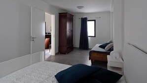 A bedroom with a bed, a wardrobe, and a window with curtains.