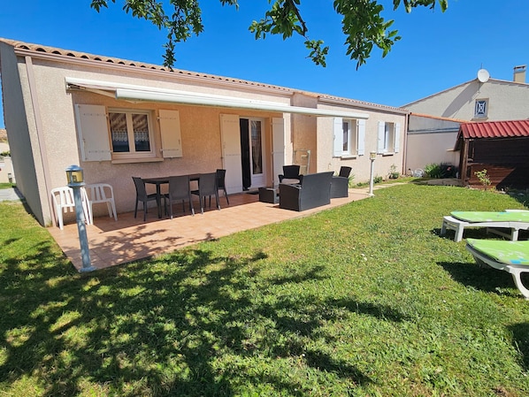 A house with a patio, outdoor furniture, and a small garden.