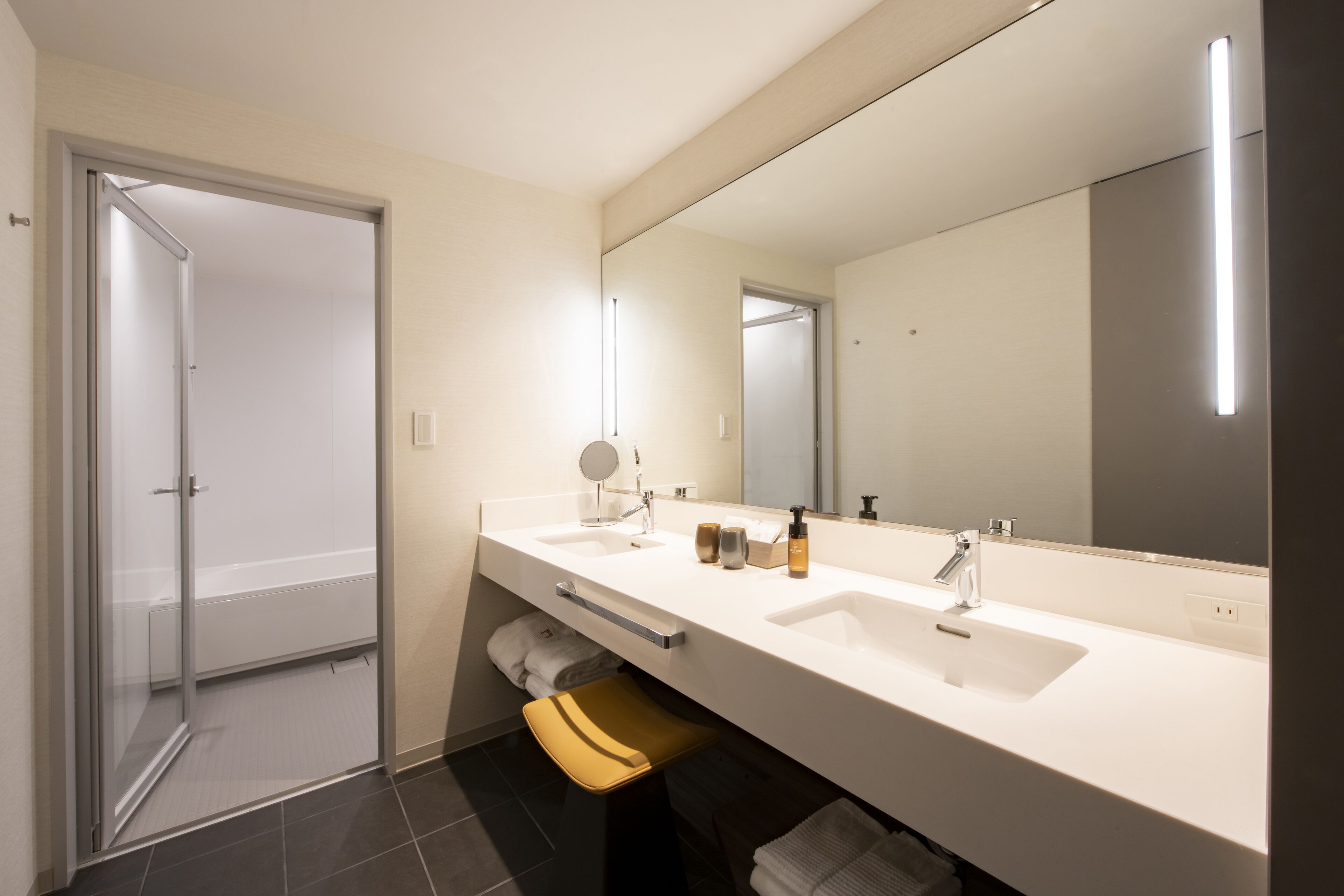 Ein modernes Badezimmer mit zwei Waschbecken, einem großen Spiegel und einer Duschkabine aus Glas.