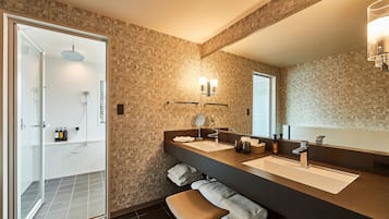 Une salle de bain moderne avec un grand miroir, deux lavabos, une douche et un banc.
