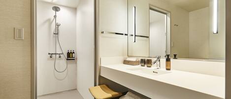 A modern bathroom with a walk-in shower, a vanity with a large mirror, and neatly folded towels.