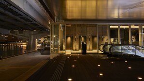 Un edificio moderno con acceso de vidrio, una escalera mecánica y vistas al río.