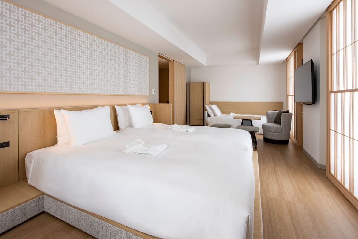 A hotel room with a large bed, a desk, a chair, and a TV.