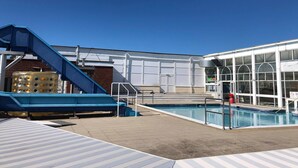 Una zona de piscina con un tobogán azul y un depósito de agua.