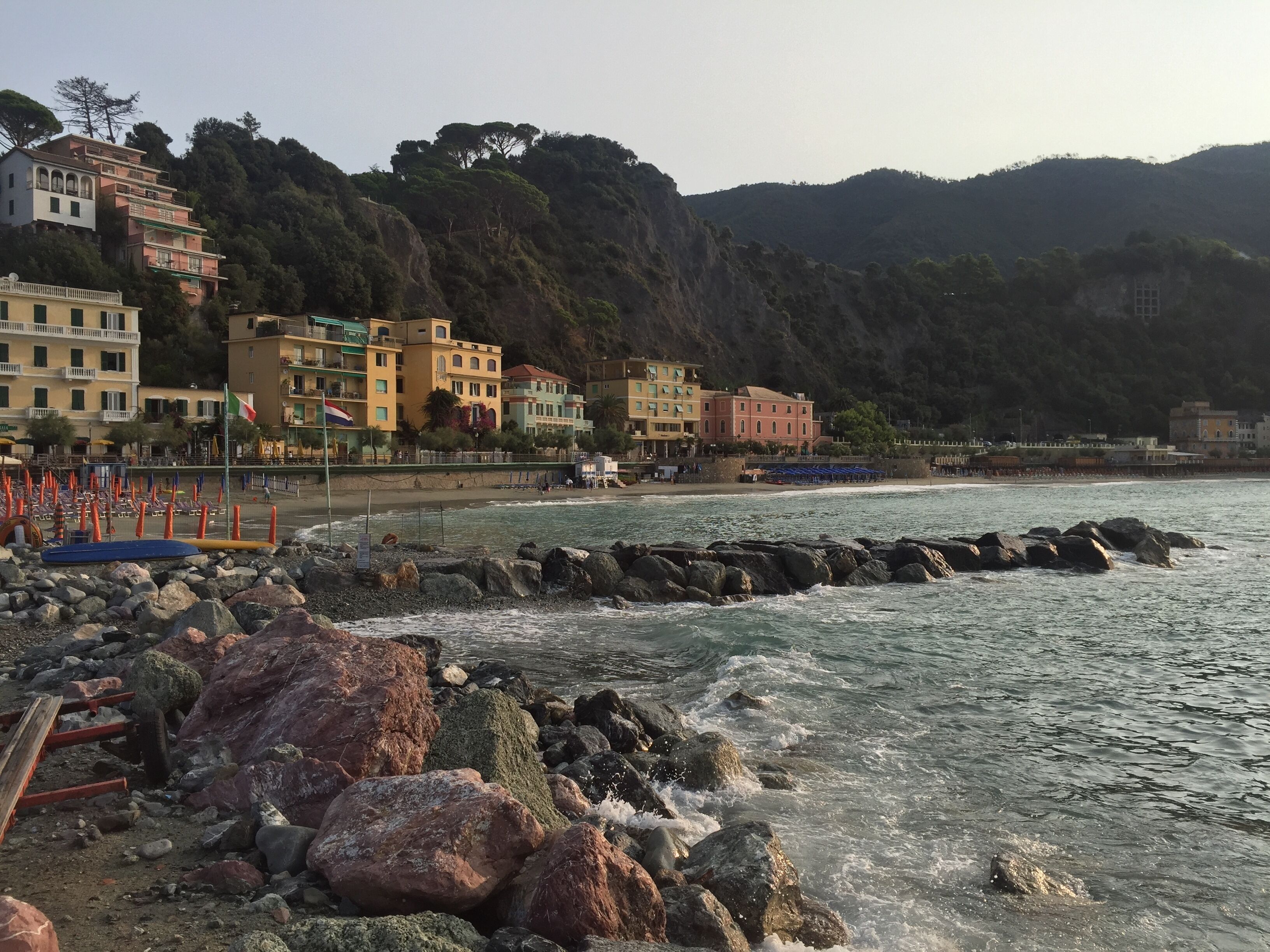 Une ville côtière avec des bâtiments qui bordent la plage, une plage rocheuse et des vagues qui s’écrasent contre les rochers.