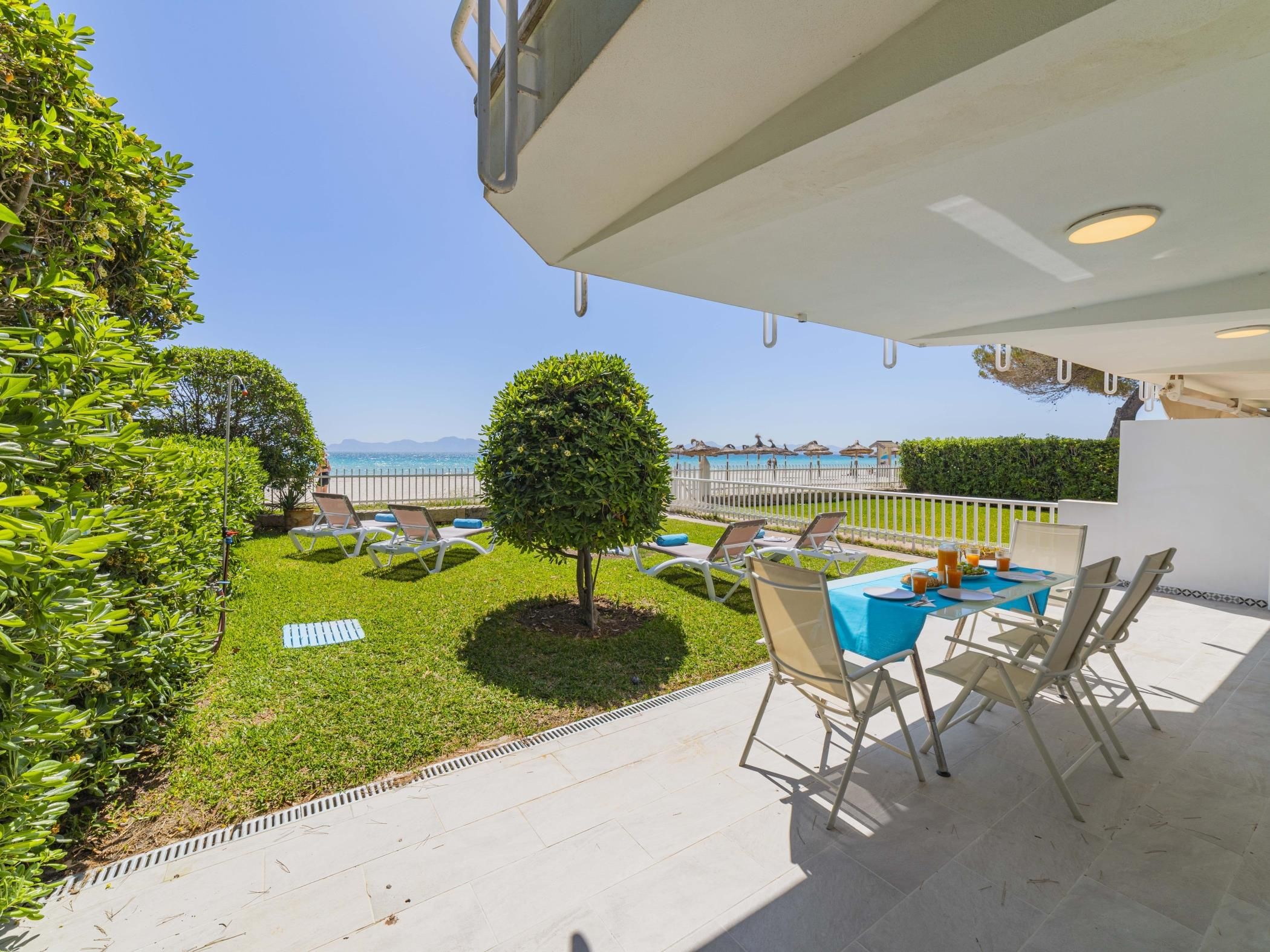 A terrace with a table and chairs, a small tree, and a view of the sea.