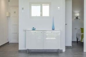 A modern bathroom with a white vanity, a mirror, and a blue vase.