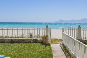 A pathway leading to a beach with a white fence and a stone wall.