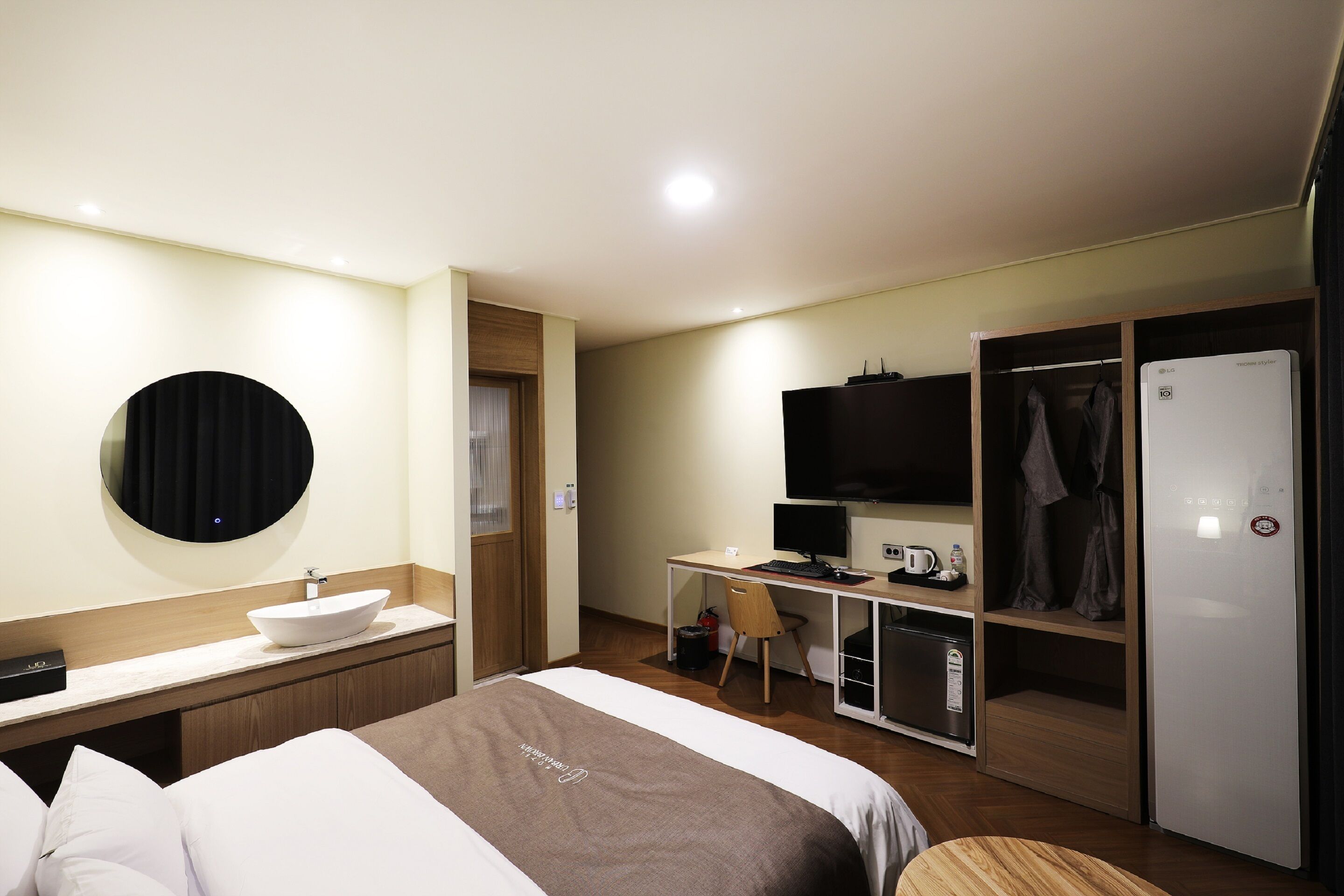 A hotel room with a bed, a desk, a TV, a minibar, and a wardrobe.