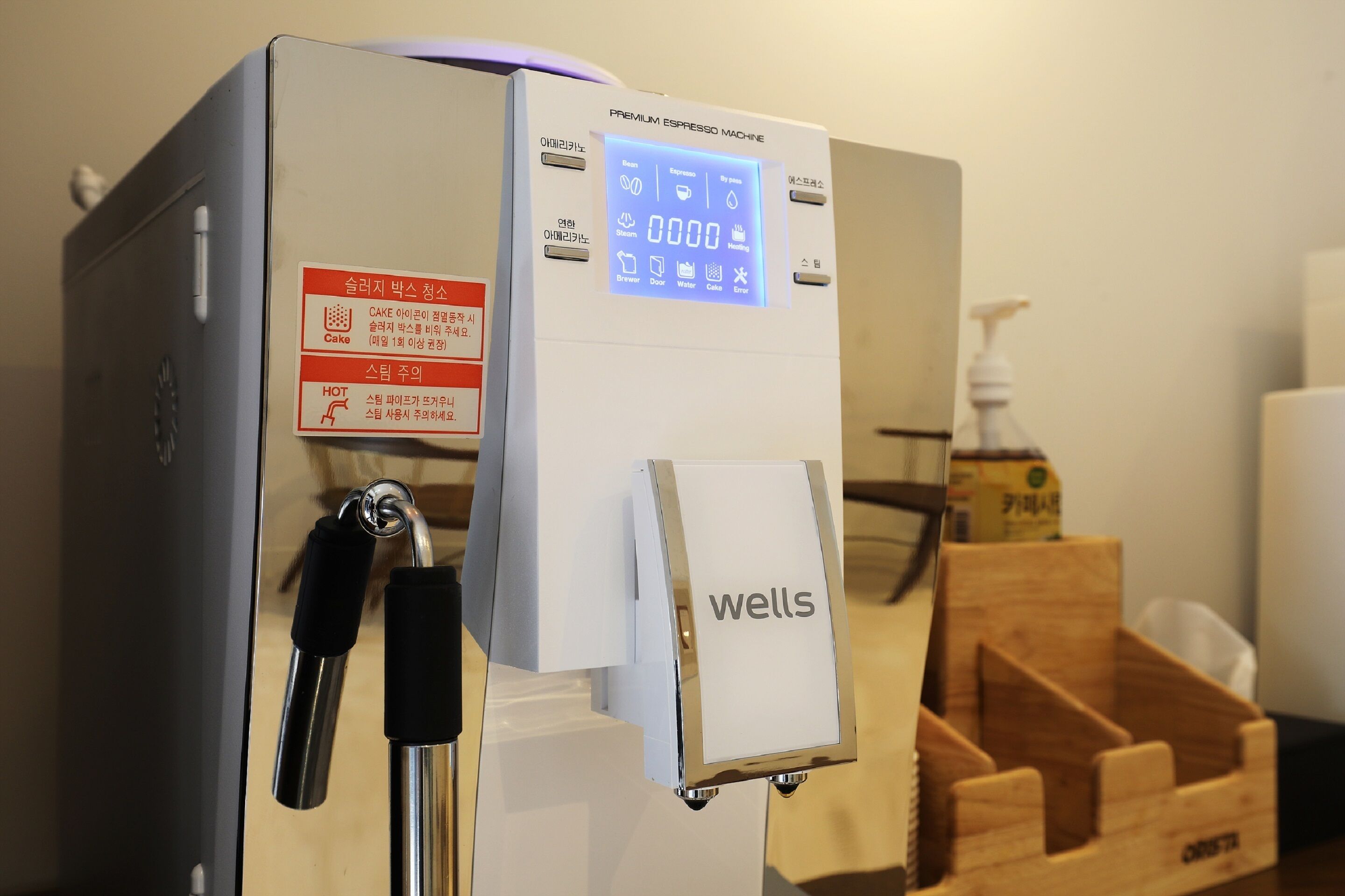 Una máquina de café con pantalla digital, dispensador de agua caliente y una etiqueta que dice 'wells'.