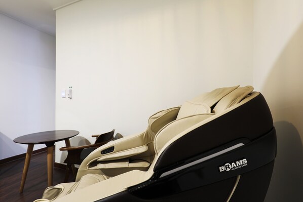 A massage chair branded 'BRAMS' in a room with a small round table and a chair. - Hotel Urban Brown (Daejeon)