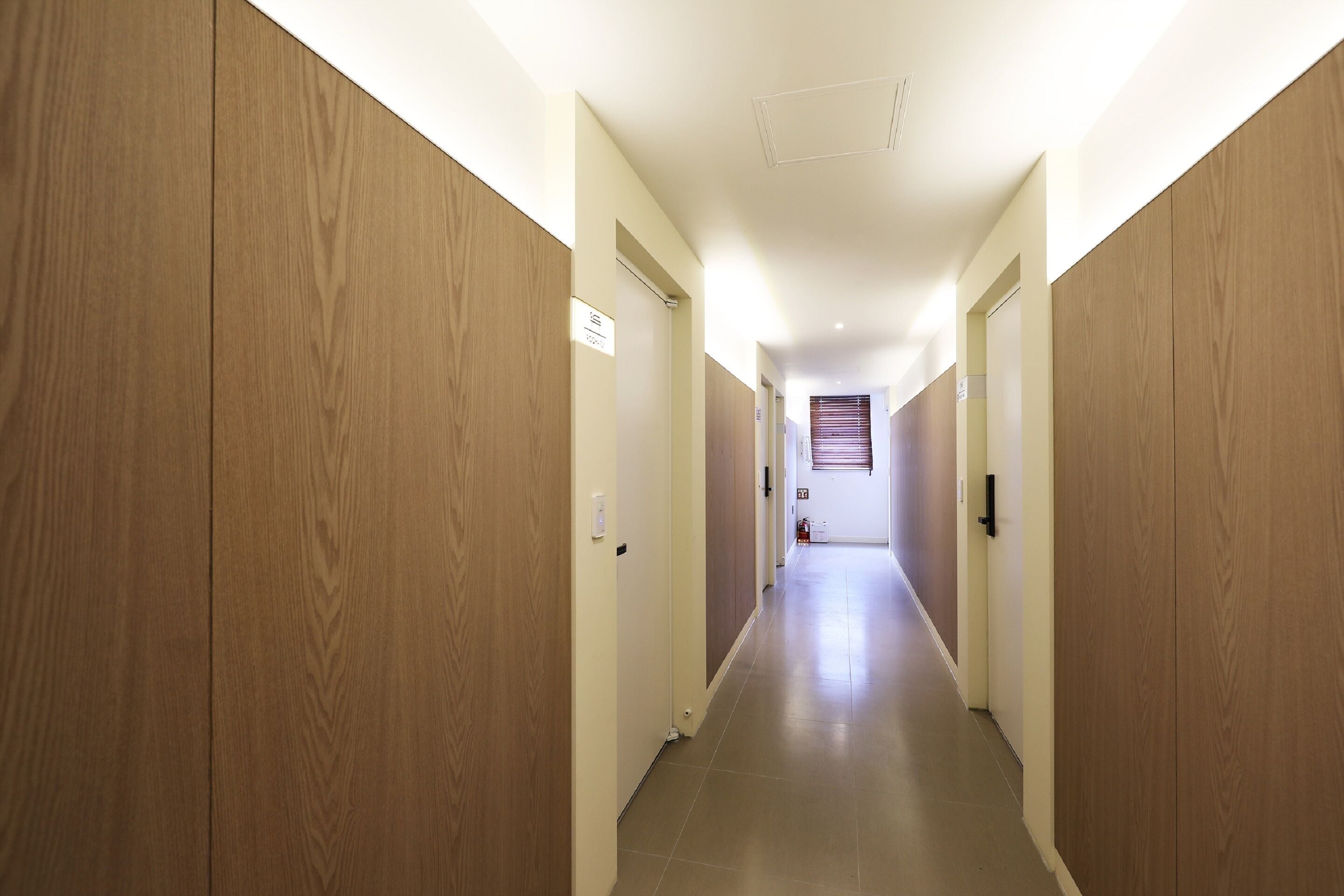Ein Flur mit Holzvertäfelung an den Wänden, gefliestem Boden und einer Tür am Ende mit einem Fenster.