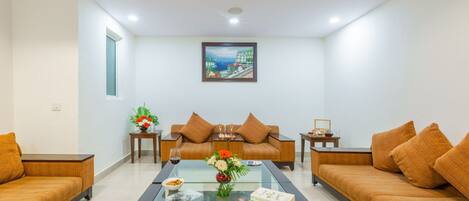 A modern living room with a glass coffee table, two sofas, a painting on the wall, and a window.