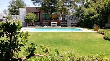 A backyard with a swimming pool, a barbecue area, and a small shed.