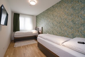 Un dormitorio con dos camas, un espejo, una mesita de noche y una ventana con cortinas.
