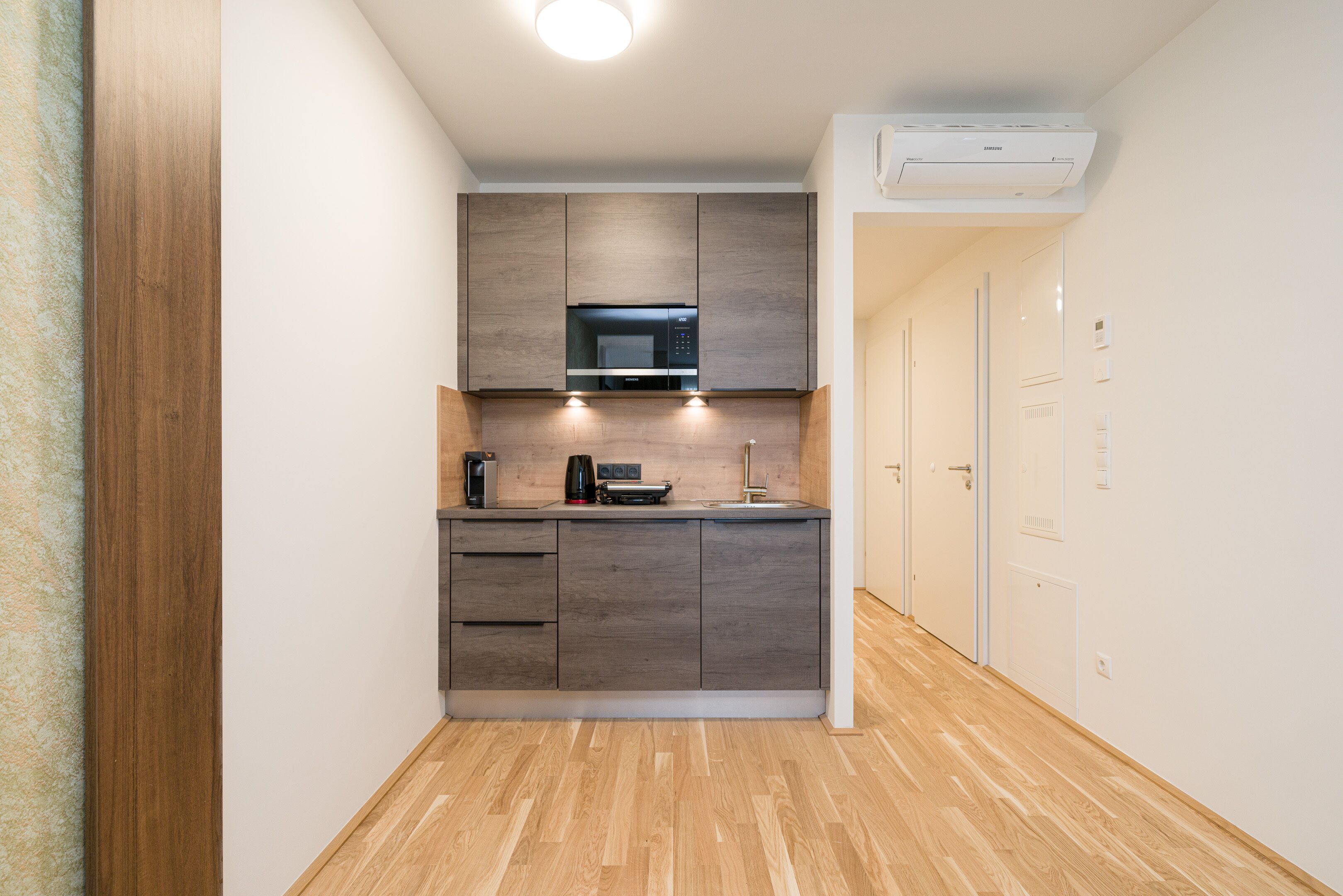 A compact kitchen with a microwave, coffee maker, and cabinets.