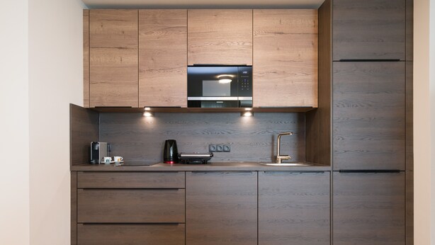 Una cocina moderna con armarios de madera, microondas integrado y cafetera.