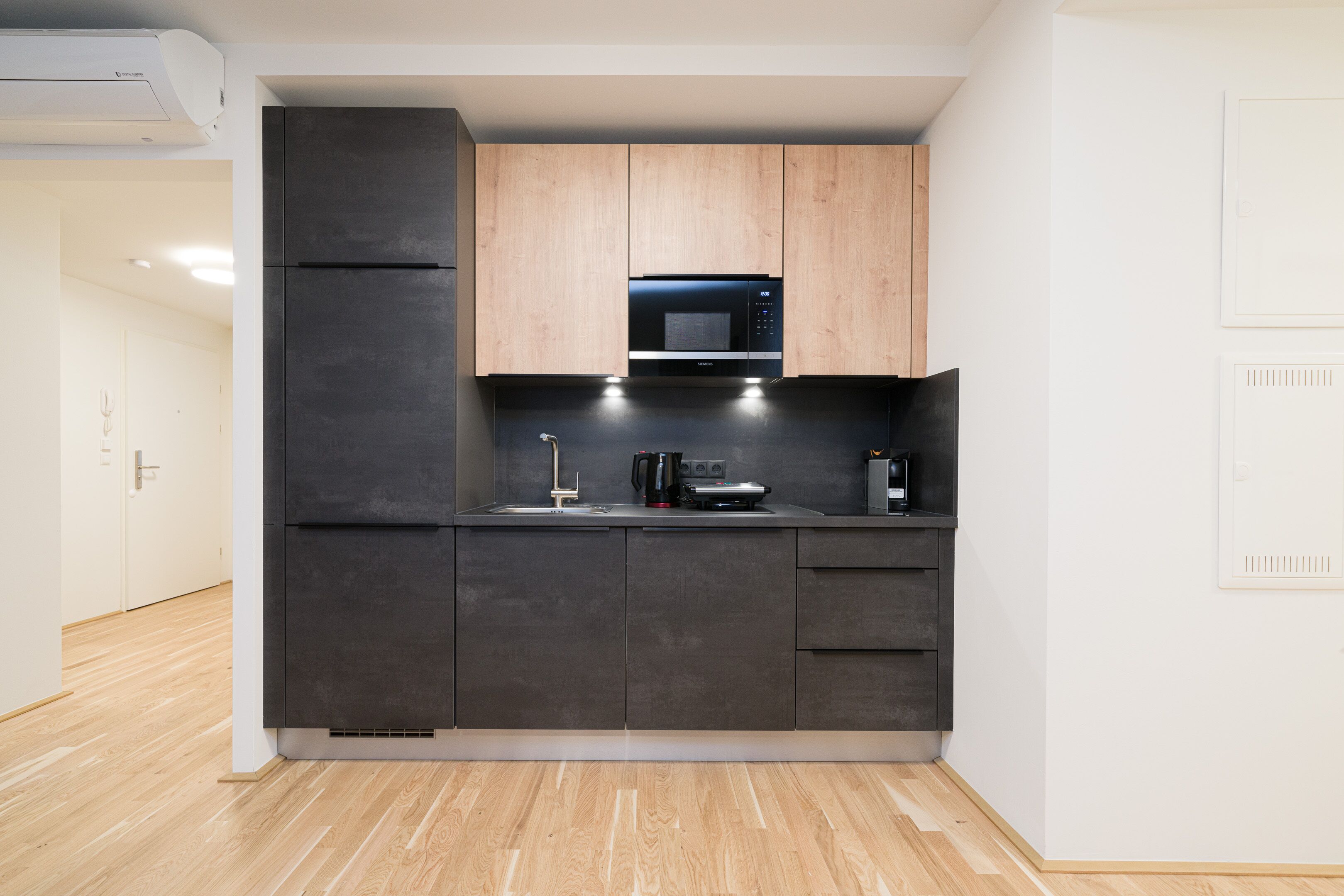 A modern kitchen with dark cabinets, a microwave, and a coffee maker.