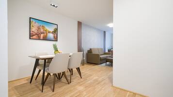 A modern living room with a sofa, a coffee table, and a dining area with a table and chairs.