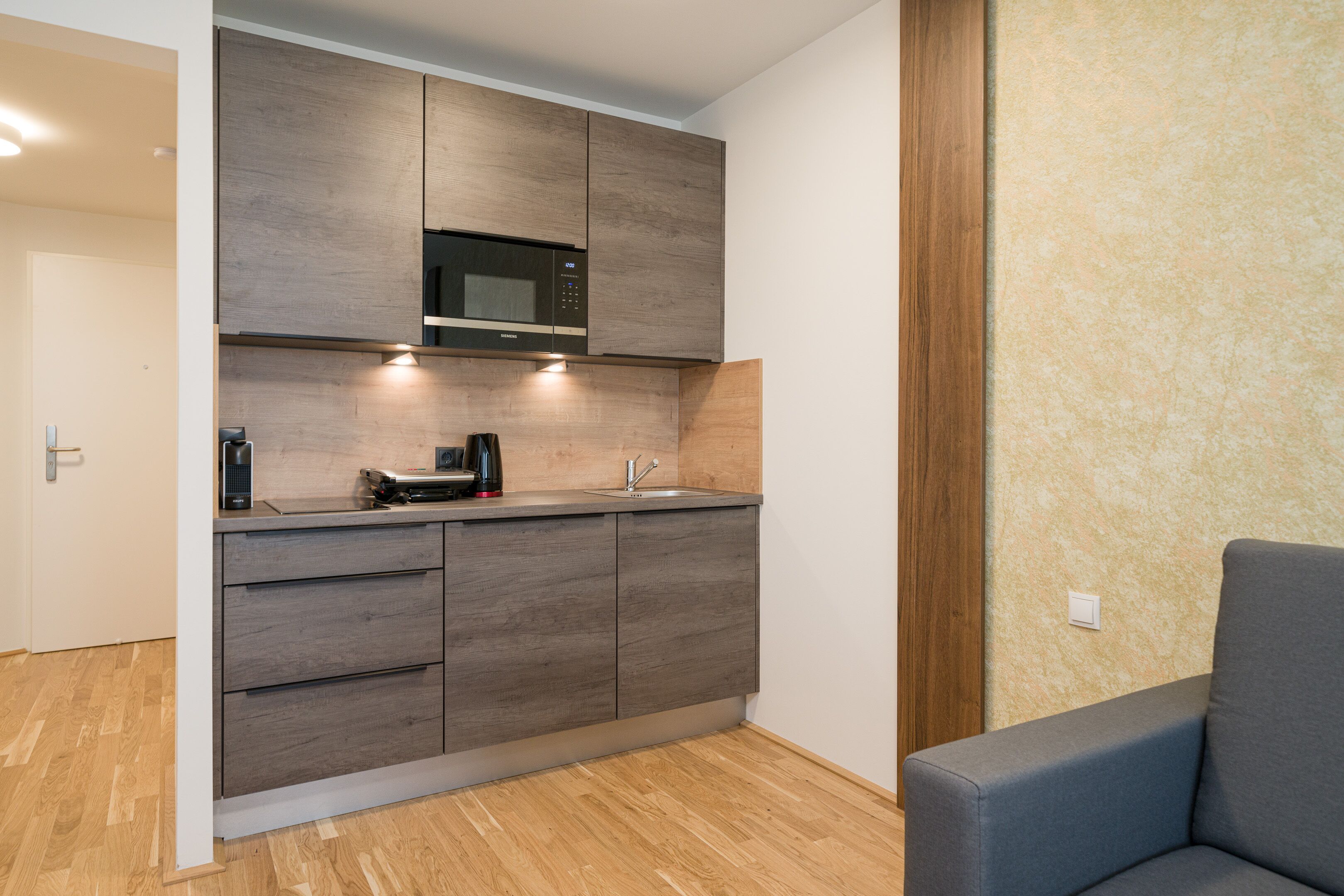 Eine moderne Küche mit Holzausstattung, einer integrierten Mikrowelle und einer Kaffeemaschine.