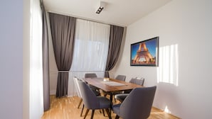 Un comedor moderno con una mesa de madera, seis sillas y un ventanal con cortinas.