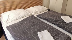 A double bed with a checkered bedspread, a wooden headboard, and a framed picture of a sunset over a pier on the wall. - A Plus Hostel - Centrum (Prague)