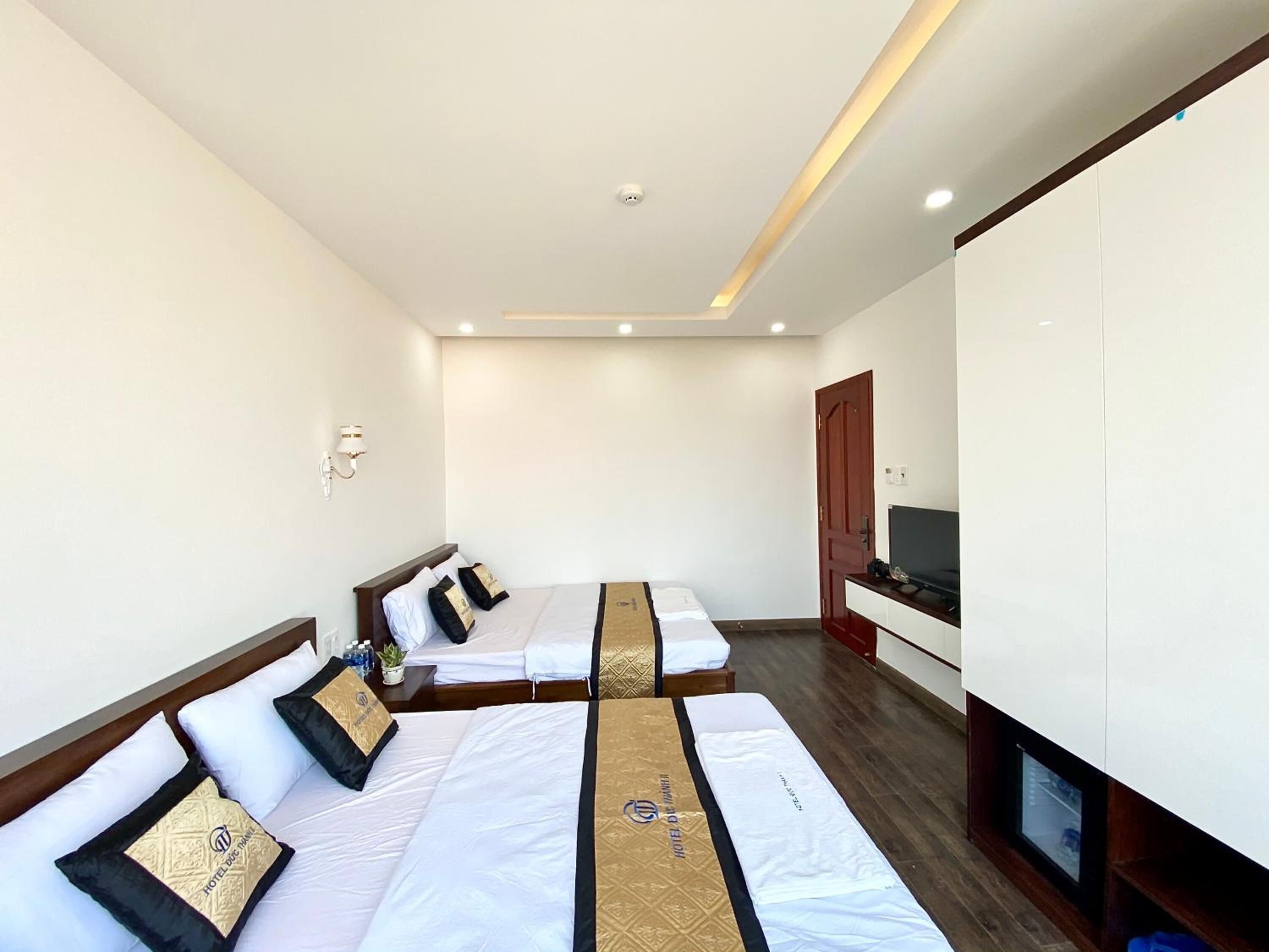 A hotel room with a large bed, a smaller bed, a desk, and a TV.
