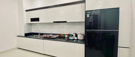 Una cocina moderna con armarios blancos, un refrigerador negro y una estufa a gas.