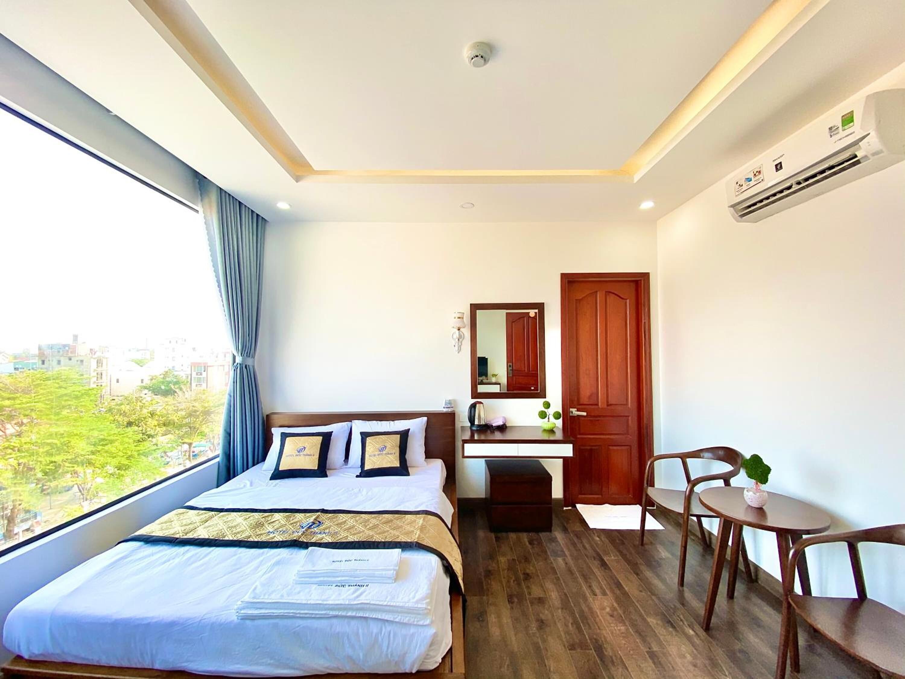 A hotel room with a large bed, a desk, a chair, and a view of the city.
