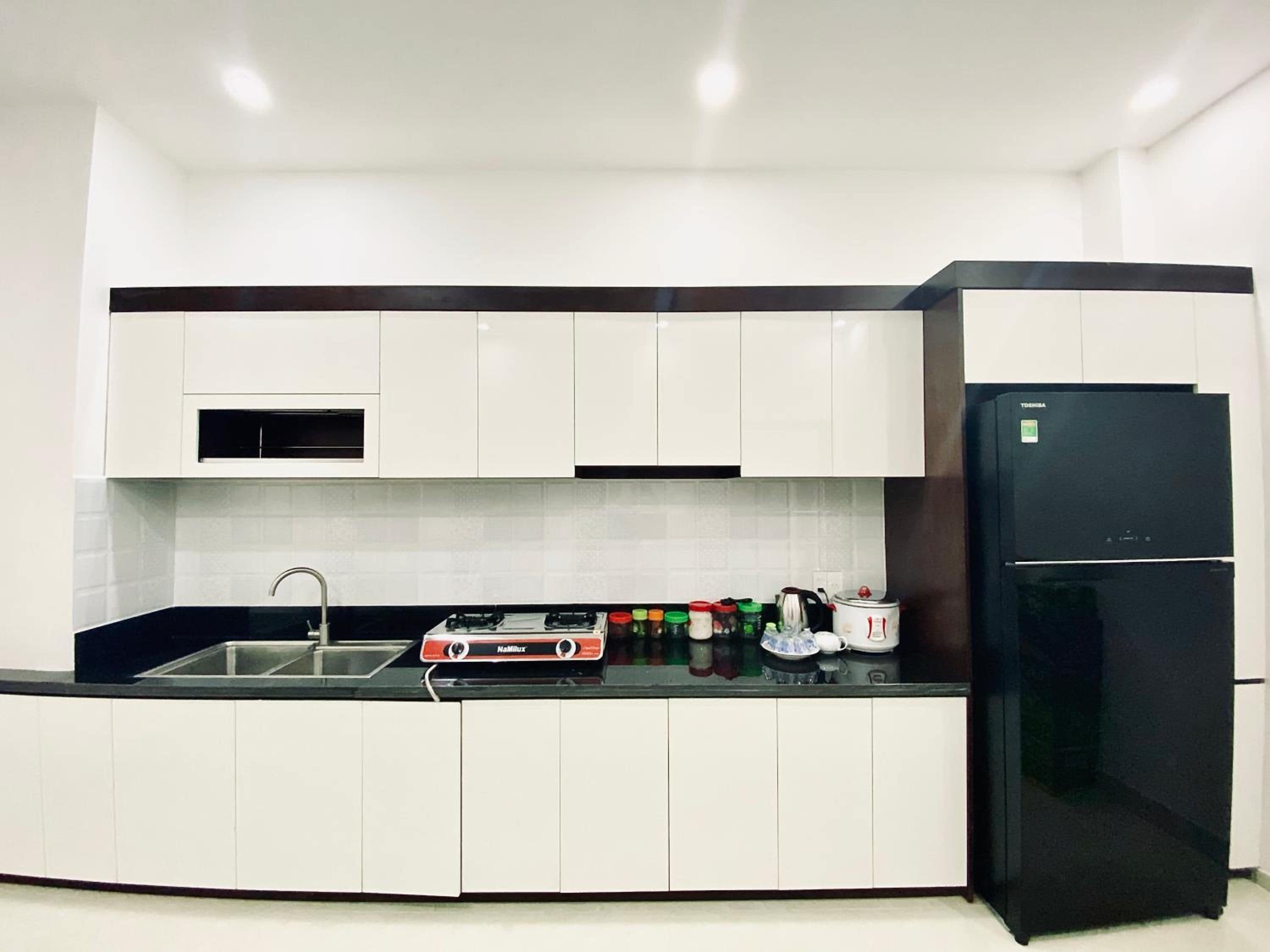 A modern kitchen with white cabinets, a black refrigerator, and a gas stove.