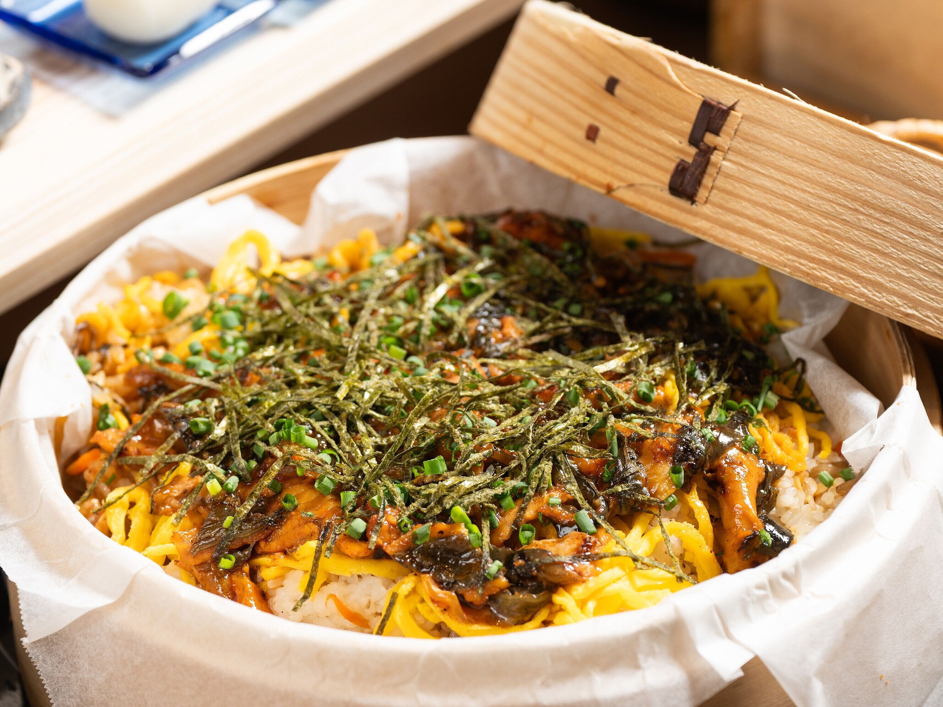 A dish with rice, vegetables, and seaweed garnished with green onions.