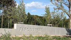 Opastekyltti, jossa lukee ”PARC DU FORT”, ja sen ympärillä on puita ja taivas on kirkas.