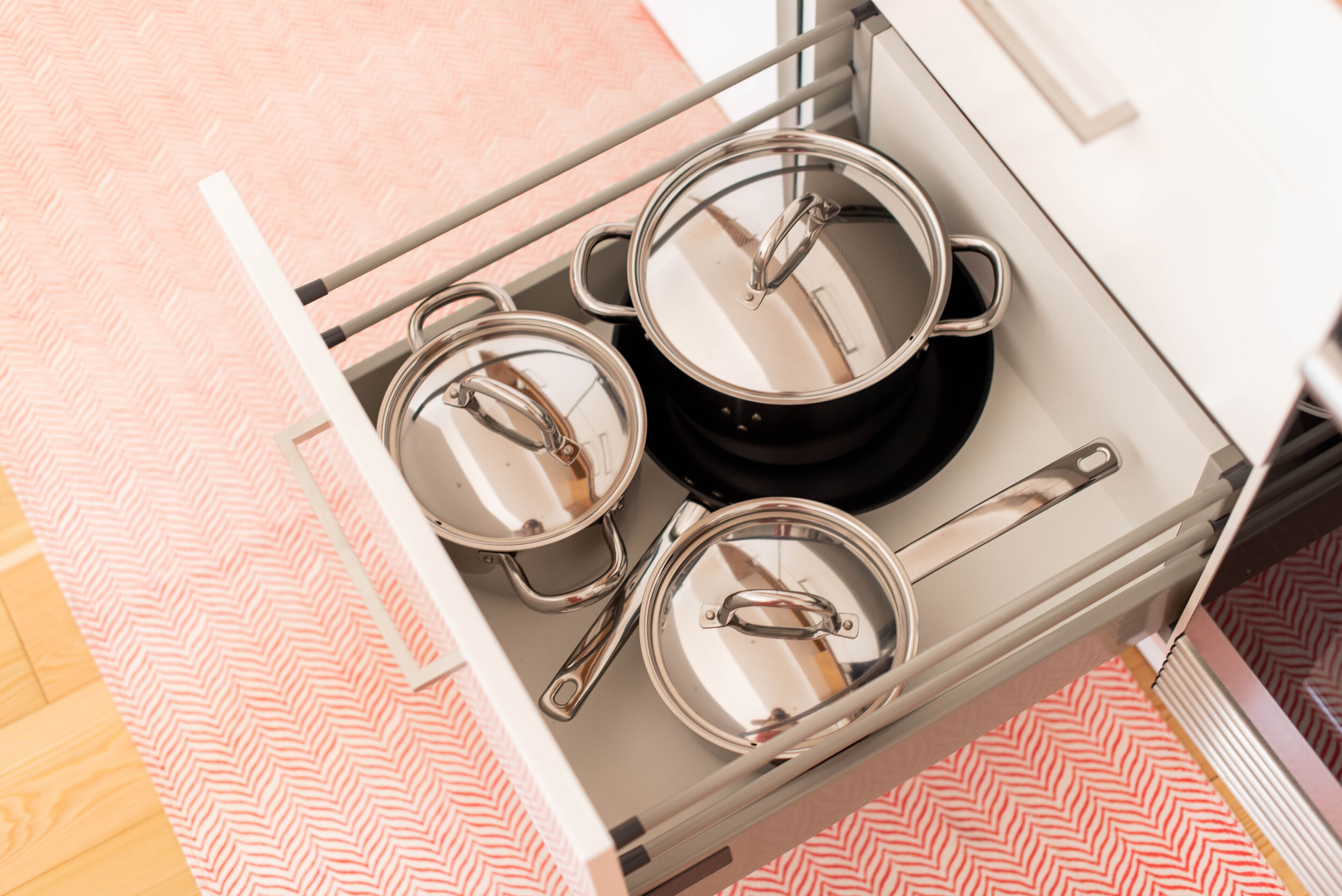 A kitchen with a stainless steel range hood, a black stove, and three pots with lids.