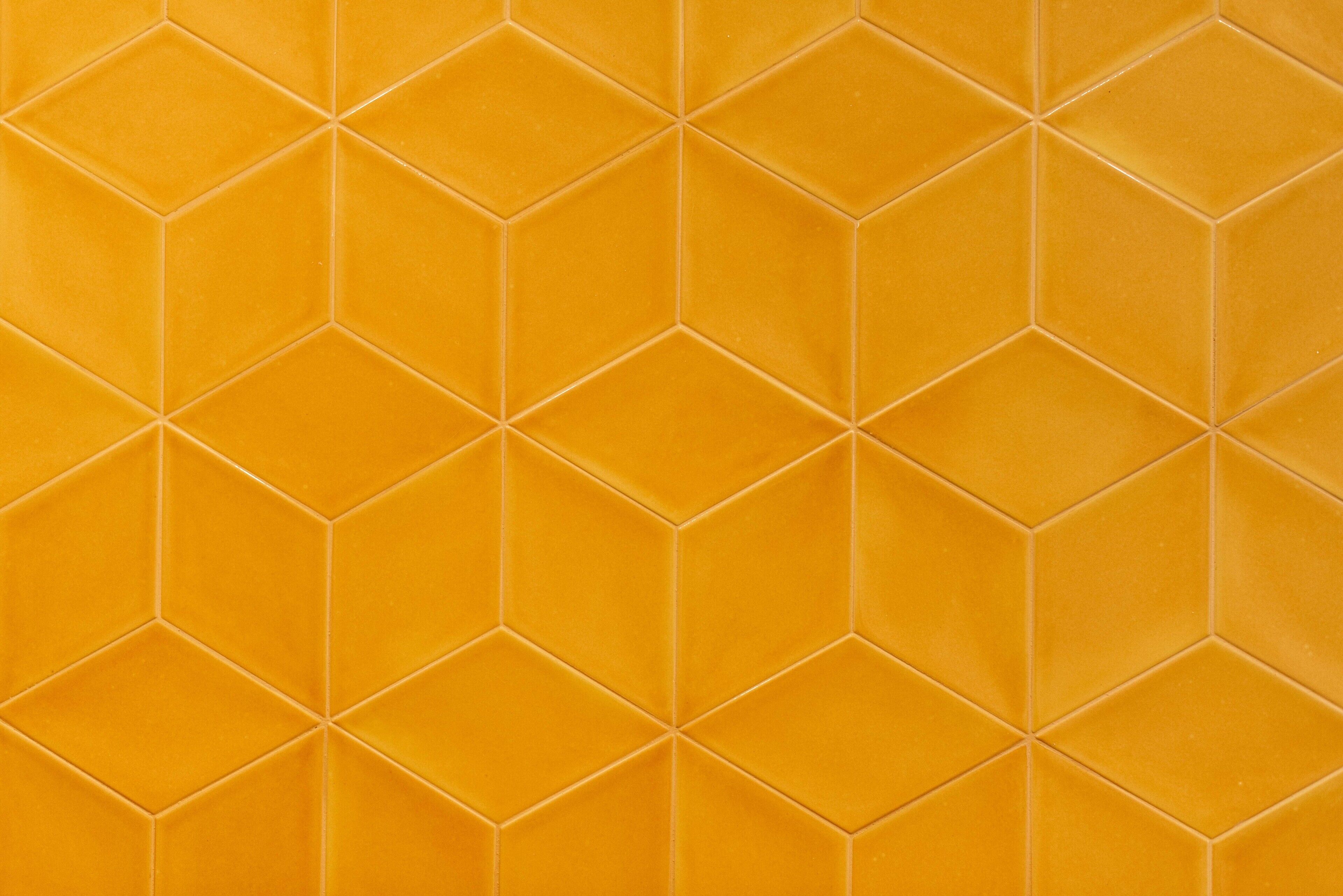A close-up of a yellow-tiled wall with a geometric pattern.