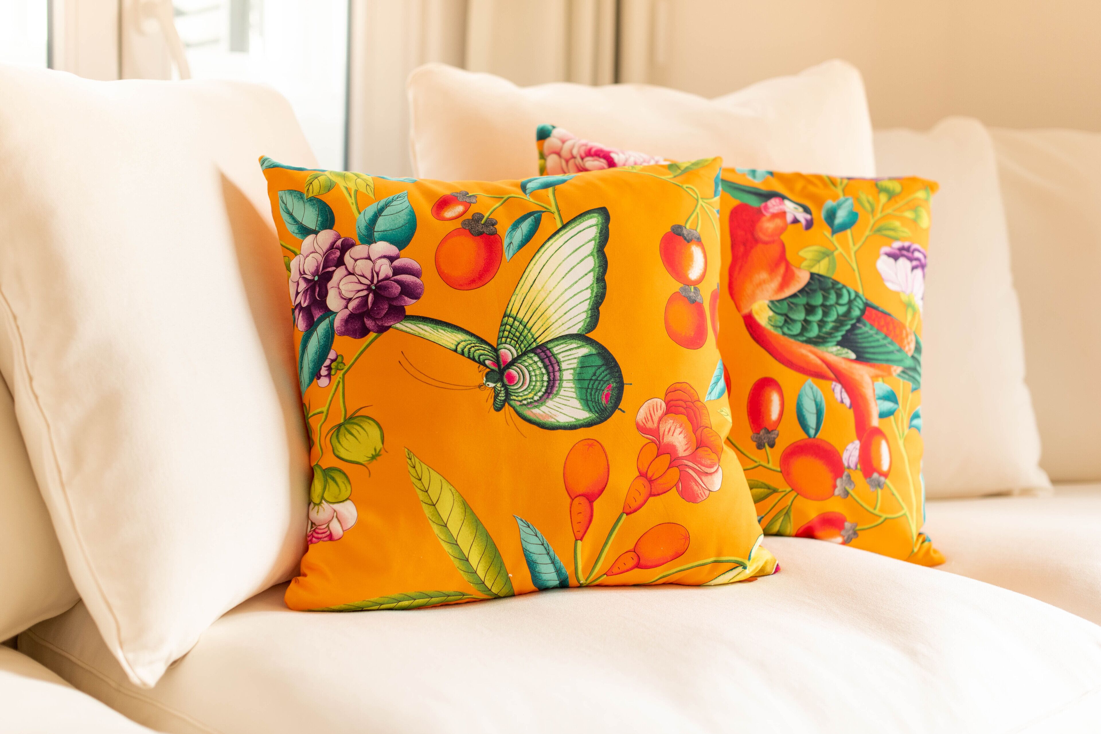 Een bed met twee kussens, versierd met een kleurrijk bloemen- en vlinderpatroon.