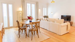 A modern living room with a dining area, a sofa set, a television, and a cabinet. - Apartamentos Ferreiros (Funchal)