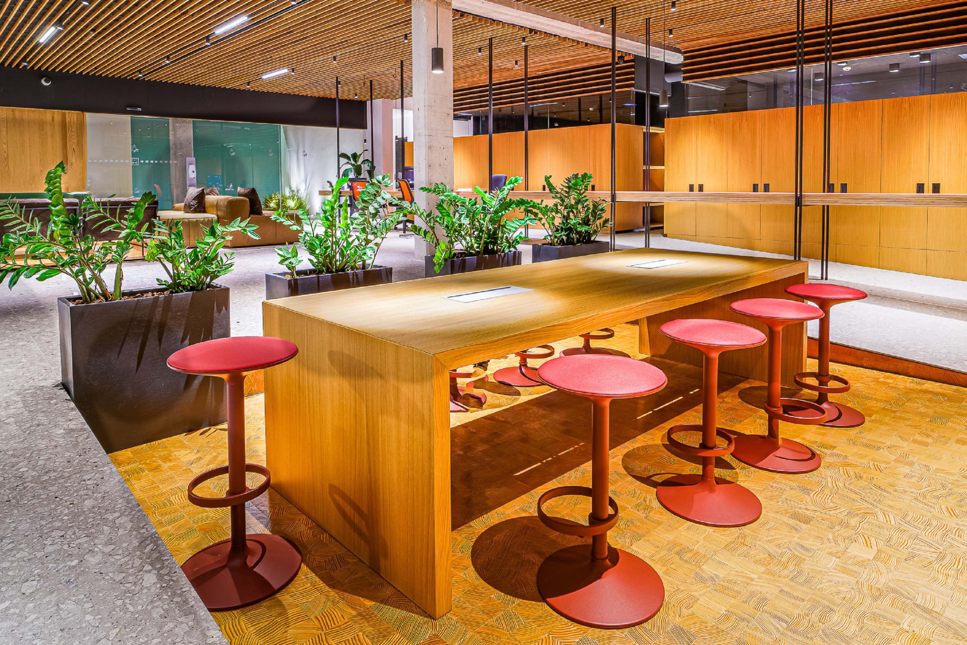 Un área de bar moderna con mostrador de madera y taburetes rojos.
