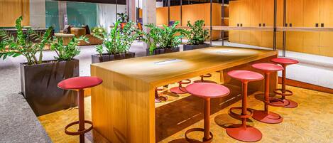 Un área de bar moderna con mostrador de madera y taburetes rojos.